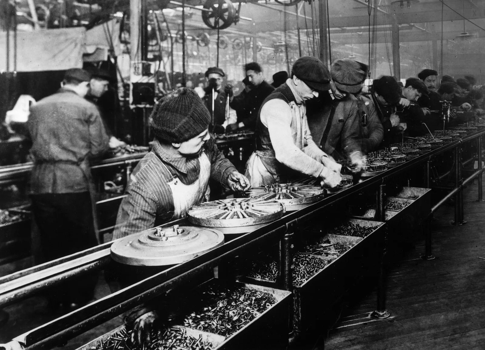 Trabajadores armando automóviles Modelo T en la línea de ensamblaje en movimiento de Ford en Highland Park, Michigan, hacia 1913