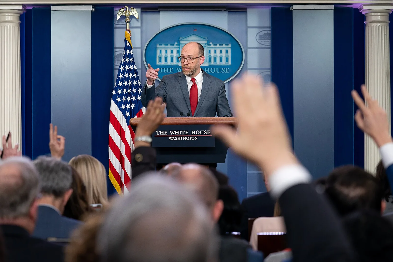 Reporters raise their hands to ask questions at a White House press briefing