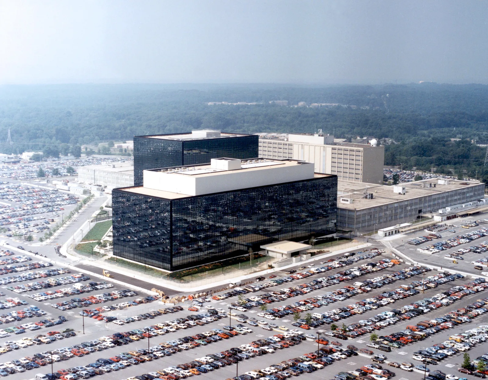 The National Security Agency's headquarters at Fort George G. Meade, Maryland: dark, mirrored glass office buildings beside a large parking lot