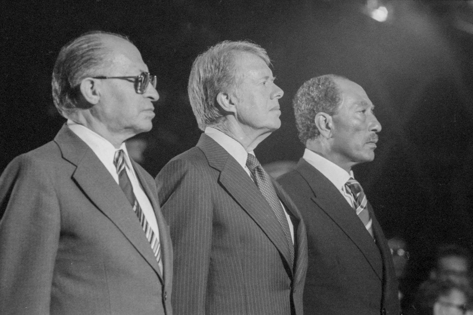 Israeli Prime Minister Menachem Begin, President Jimmy Carter, and Egyptian President Anwar Sadat standing together at Camp David during the September 1978 negotiations