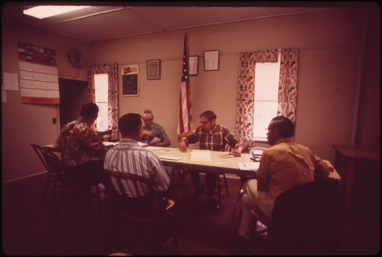 Members of a village board hold their monthly meeting seated around a table, Garland, Nebraska, 1973.