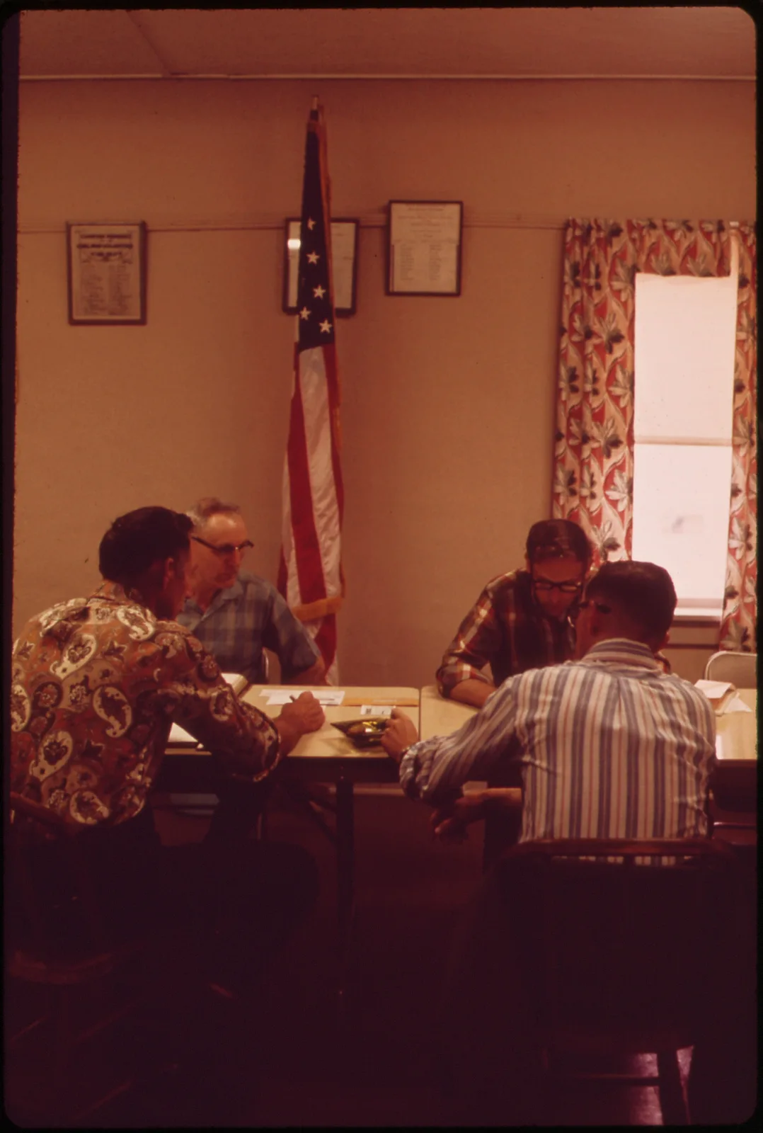 Members of the Garland Village Board sit around a table for their monthly meeting in a room above the town's volunteer fire department, Garland, Nebraska, May 1973.