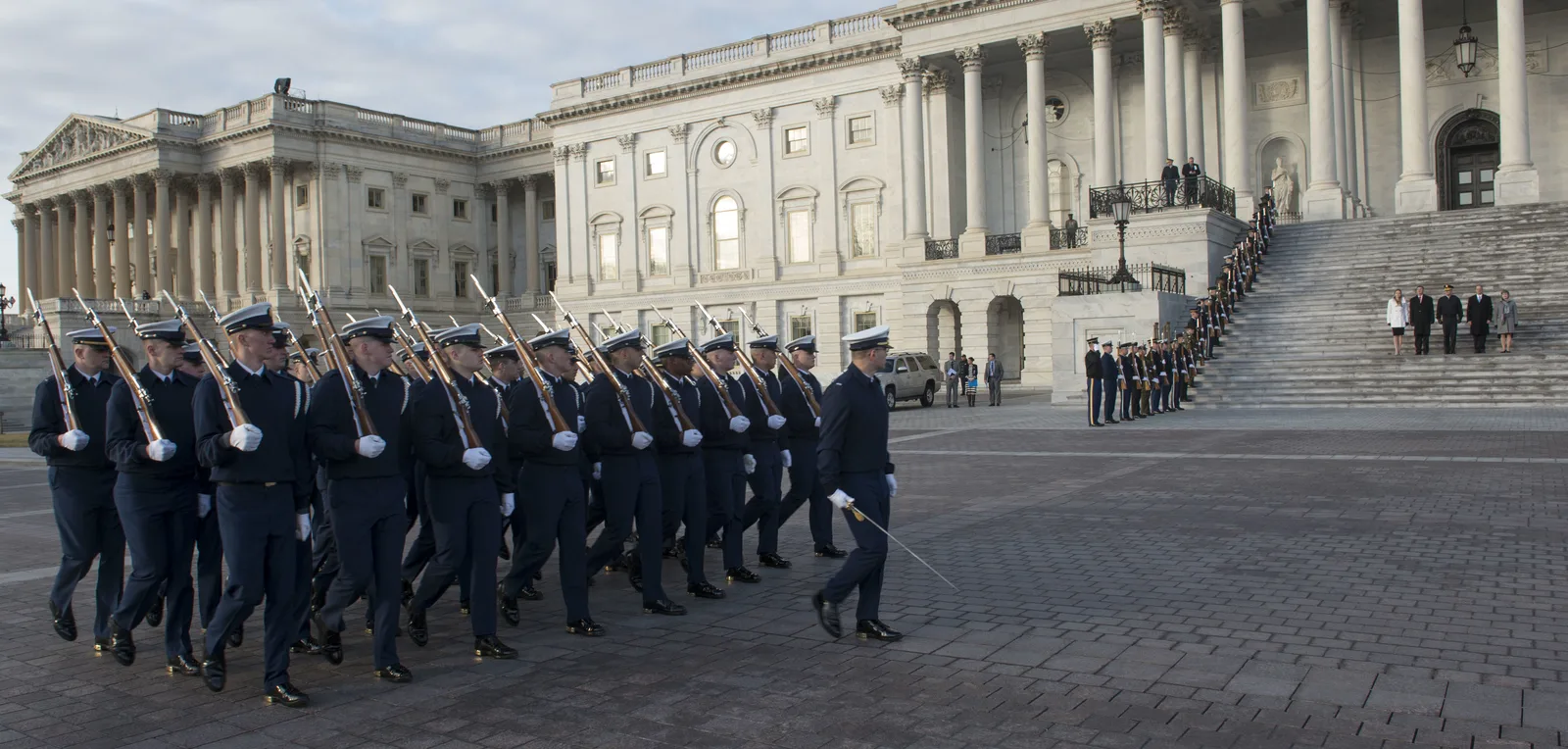 La Guardia de Honor de la Guardia Costera de EE. UU. marcha con rifles frente a la fachada este del Capitolio de EE. UU., con una fila de honor militar en las escaleras, durante el ensayo general de la toma de posesión presidencial en enero de 2017