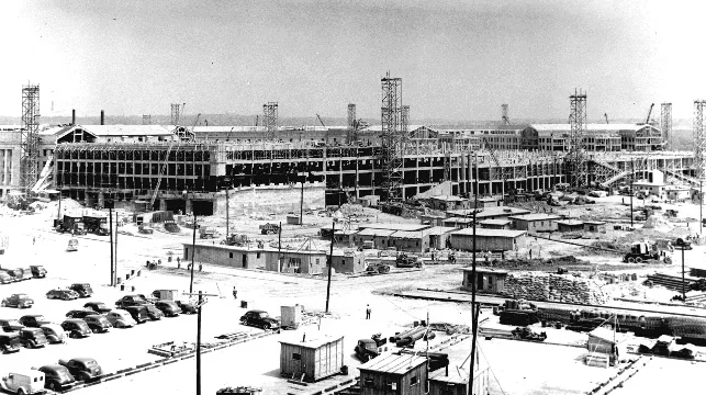 Black-and-white photograph of the Pentagon's concrete walls and scaffolding rising from a construction site, viewed from the northwest.