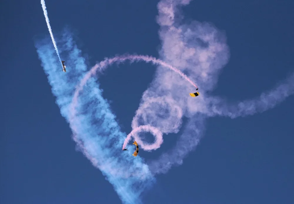 A U.S. Army Golden Knights Parachute Team member performs a canopy maneuver above a crowd at an airshow