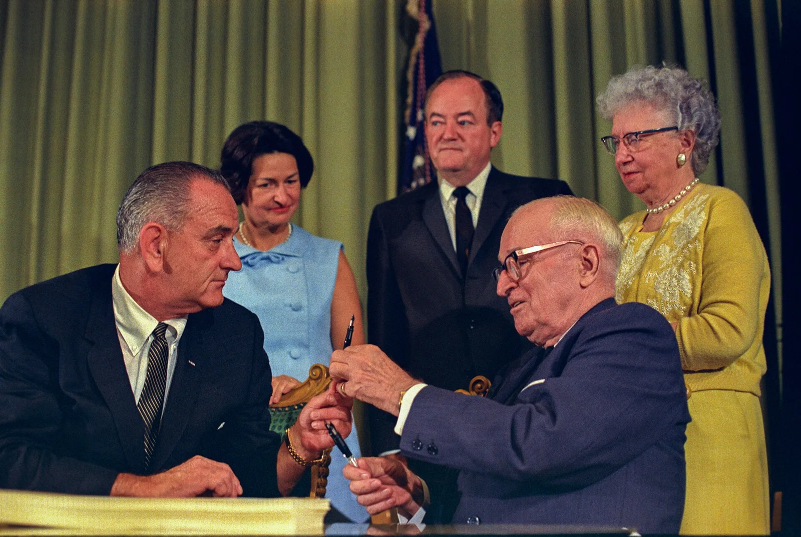 President Lyndon B. Johnson signing the Medicare bill at the Harry S. Truman Library in Independence, Missouri, July 30, 1965, with former President Truman seated beside him