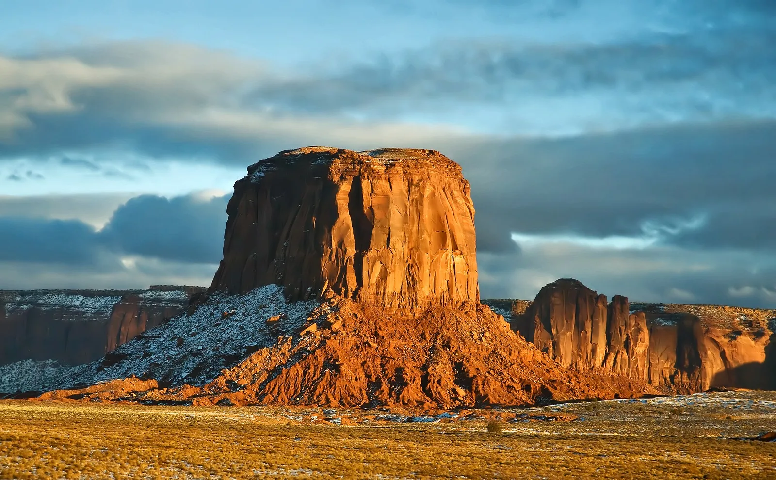 Monument Valley sandstone buttes rising from the Navajo Nation at sunset, sacred lands that have anchored the Dine people for generations and define the American Southwest