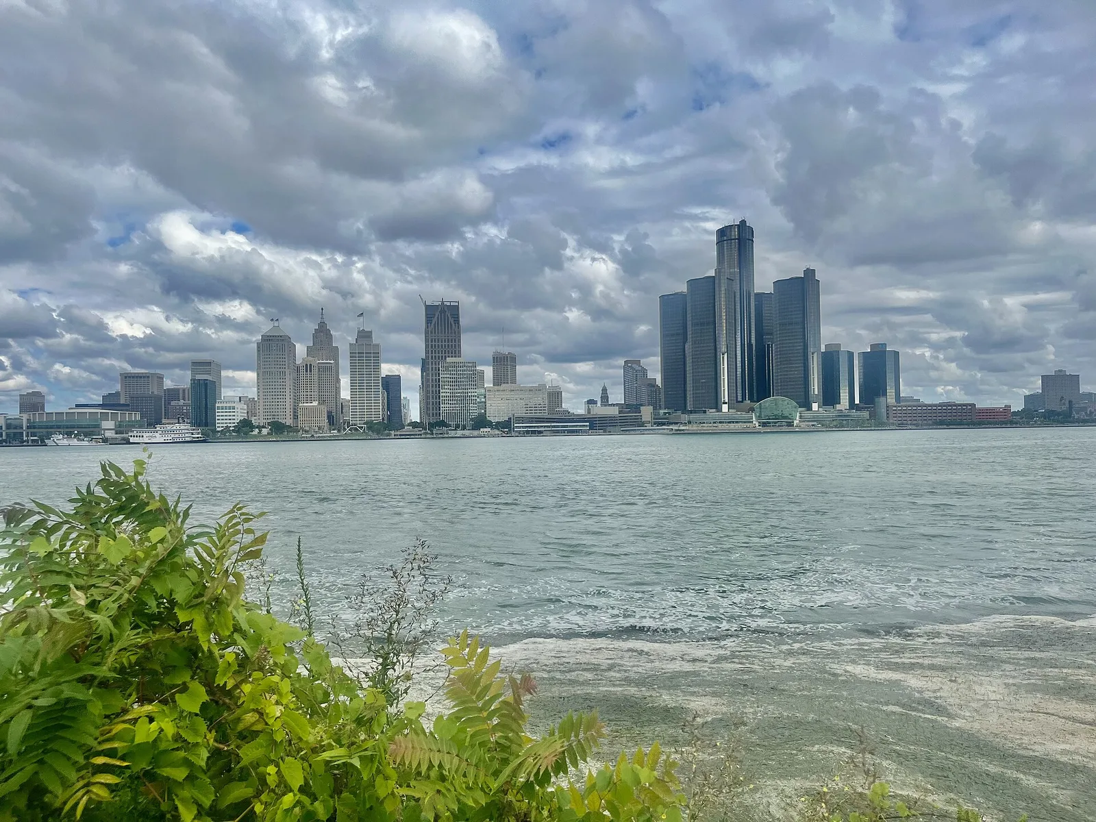 Detroit skyline at dusk reflected in the Detroit River, with the Renaissance Center prominent on the waterfront