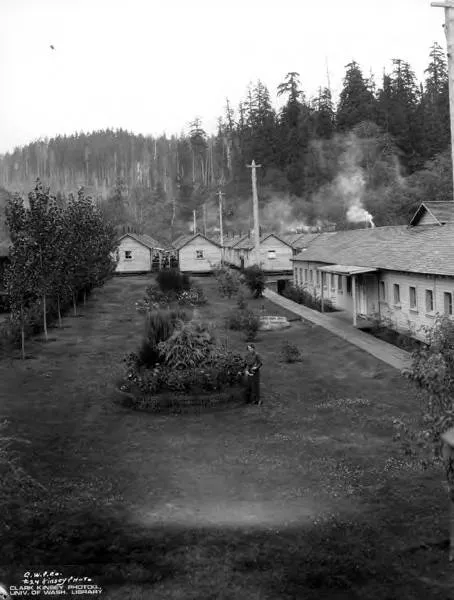 A logging camp of the Crown-Willamette Paper Company in the Oregon woods around 1925, with a tended garden beside the bunkhouses; Crown-Willamette merged into Crown Zellerbach in 1928