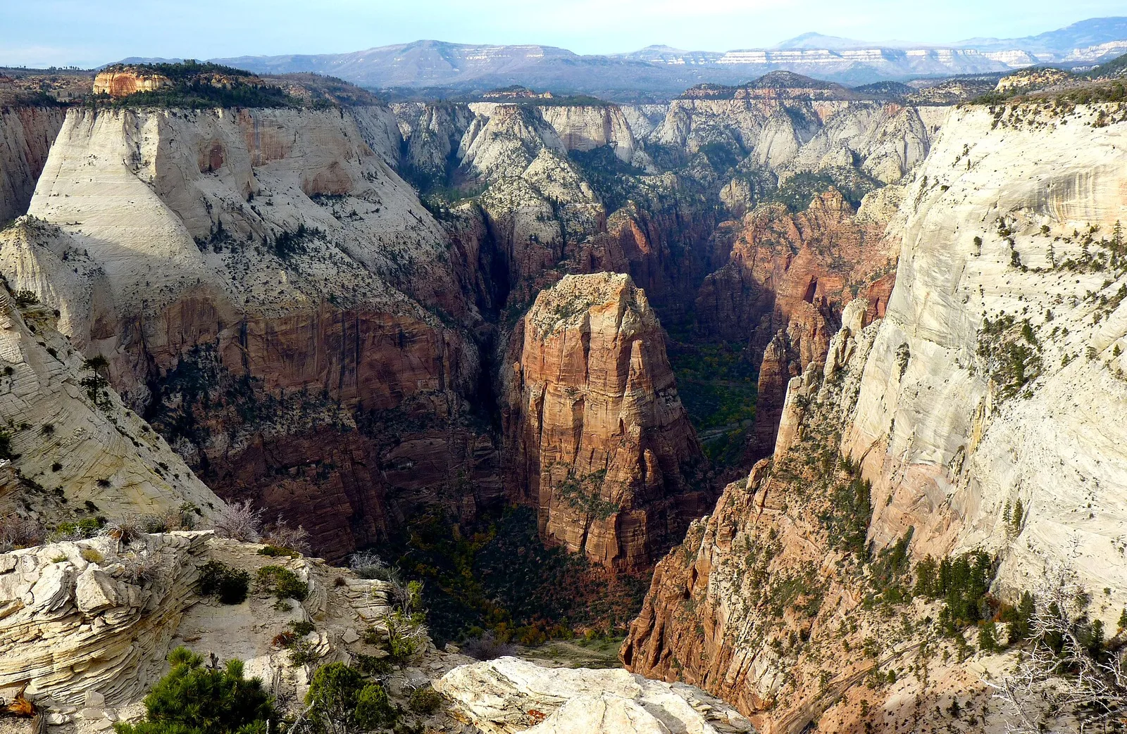 The narrow sandstone ridge of the Angels Landing trail in Zion National Park, Utah, with hikers using the chain-assisted final approach along a knife-edge ridge with sheer drop-offs on both sides
